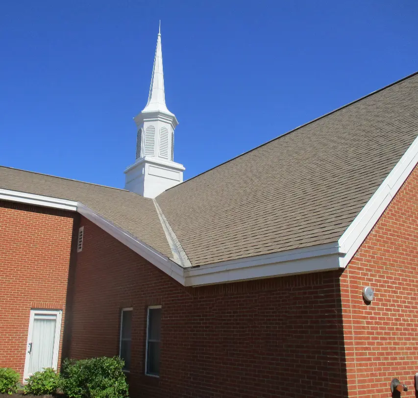 A church with a new asphalt shingle roof installed by Vanguard Roofing.