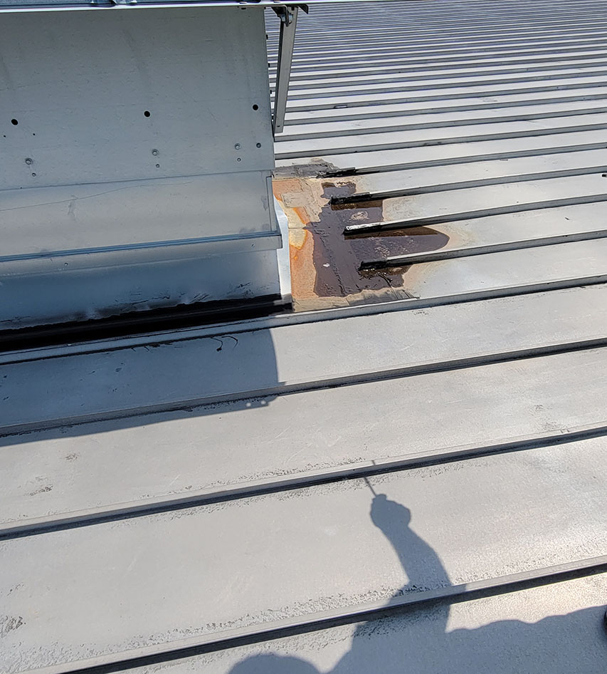 A damaged commercial metal roof before repair by Vanguard Roofing.