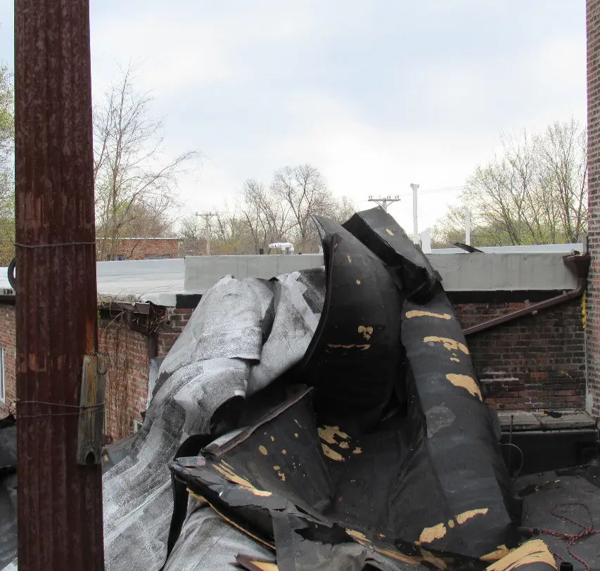 A damaged roof torn off of a building after a storm.