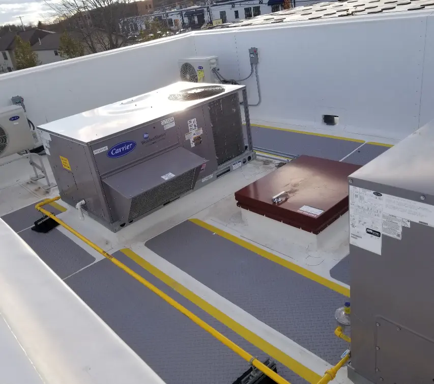 A flat commercial roof showing an access hatch and an air conditioner unit.