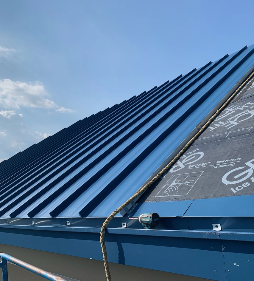 A blue commercial metal roof being installed by Vanguard Roofing.