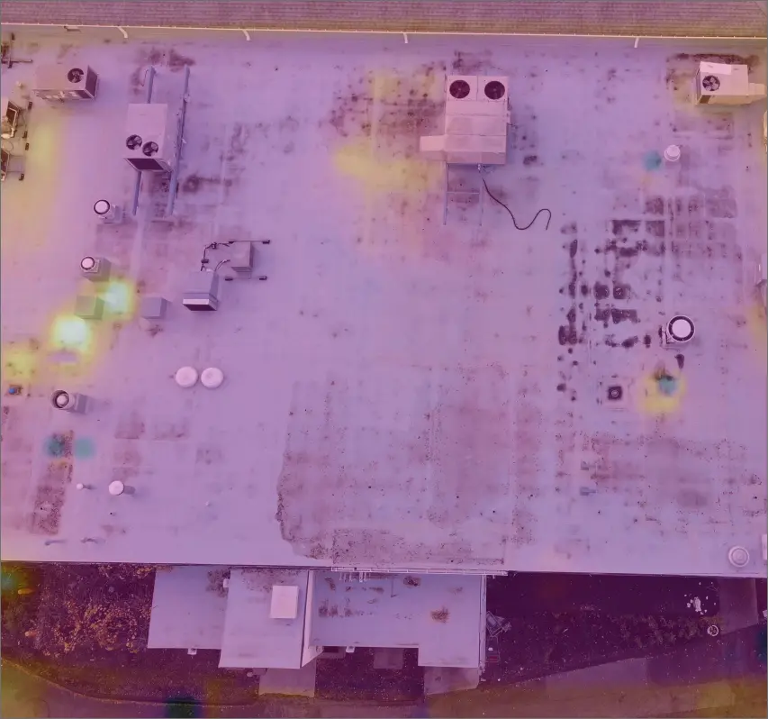 An aerial view of a thermal image showing damage on a flat commercial roof.