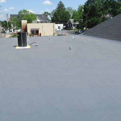 close up of new roof coating with a neighborhood in the background
