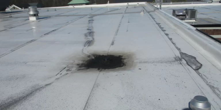 Flat white commercial roof with visible water pool