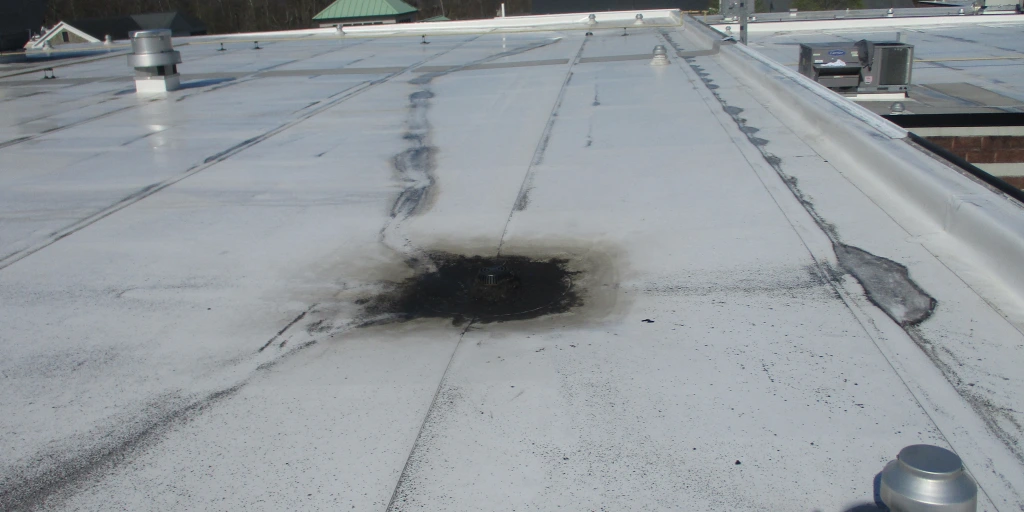 Flat white commercial roof with visible water pool