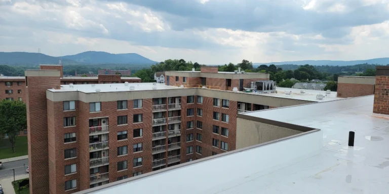 White TPO commercial flat roof on multi-story apartment building complex with mountain views in the background