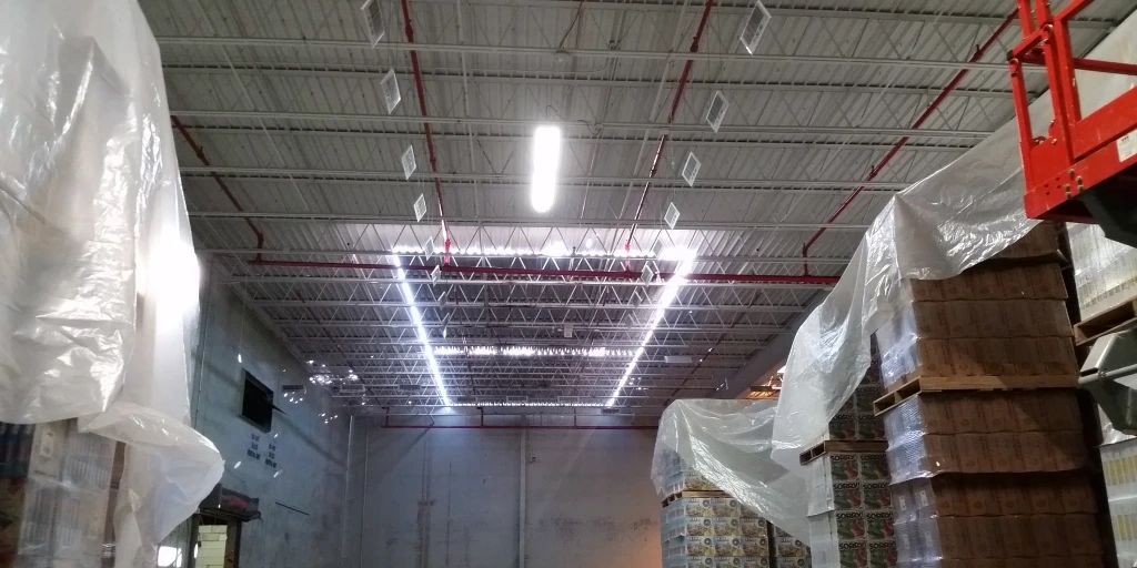 Interior view of commercial warehouse with metal deck roof and covered inventory showing water damage protection measures