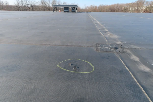 Aerial view of a large industrial flat roof with an EPDM membrane showing a marked area of damage requiring emergency repair