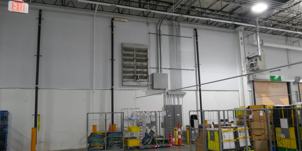 Interior of a warehouse facility showing electrical panels and conduit runs vulnerable to roof leak damage