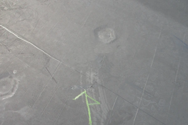 A cracked and damaged flat roof membrane on a commercial building, marked with a green arrow indicating the location of the defect.
