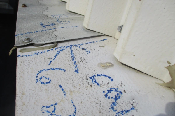 Close-up of a roof membrane marked with blue paint pen during a roofing contractor inspection.