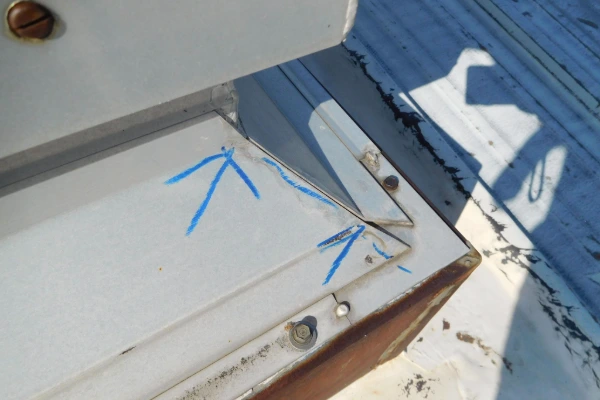 Close-up of a metal roof flashing corner marked for repair during a roof inspection.