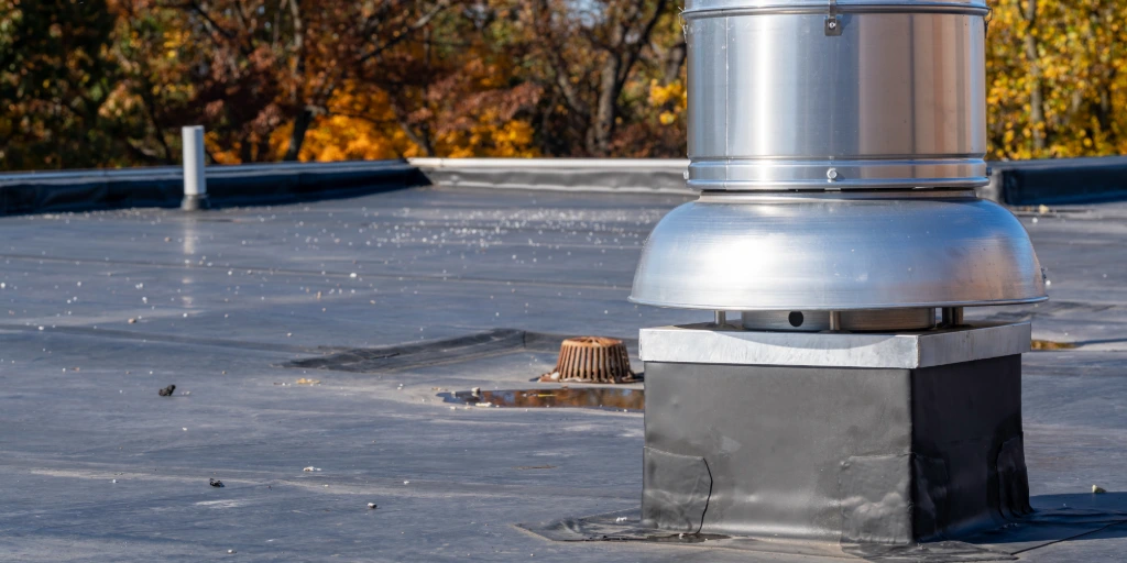 Rooftop exhaust fan and drain on a commercial flat roof during a fall maintenance inspection