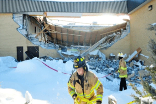 Firefighters responding to a commercial roof collapse caused by heavy snow load
