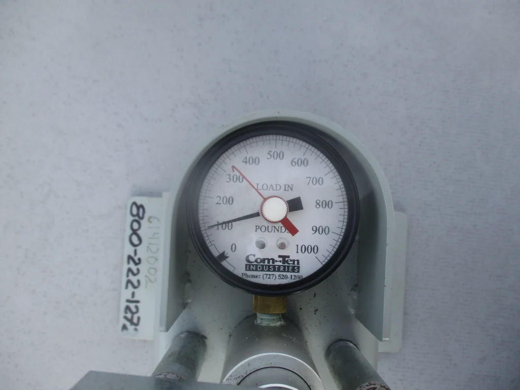 Close-up of a roof pull test gauge recording fastener pull-out force on a single-ply membrane